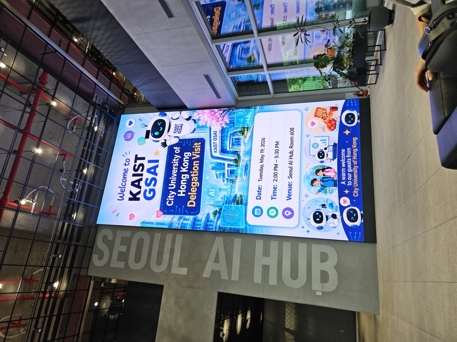 A large screen reading 'Welcome to KAIST GSAI — City University of Hong Kong Delegation Visit'