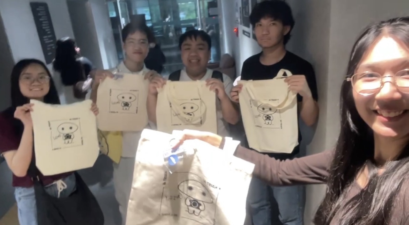 Students holding up KAIST's hand-illustrated tote bags