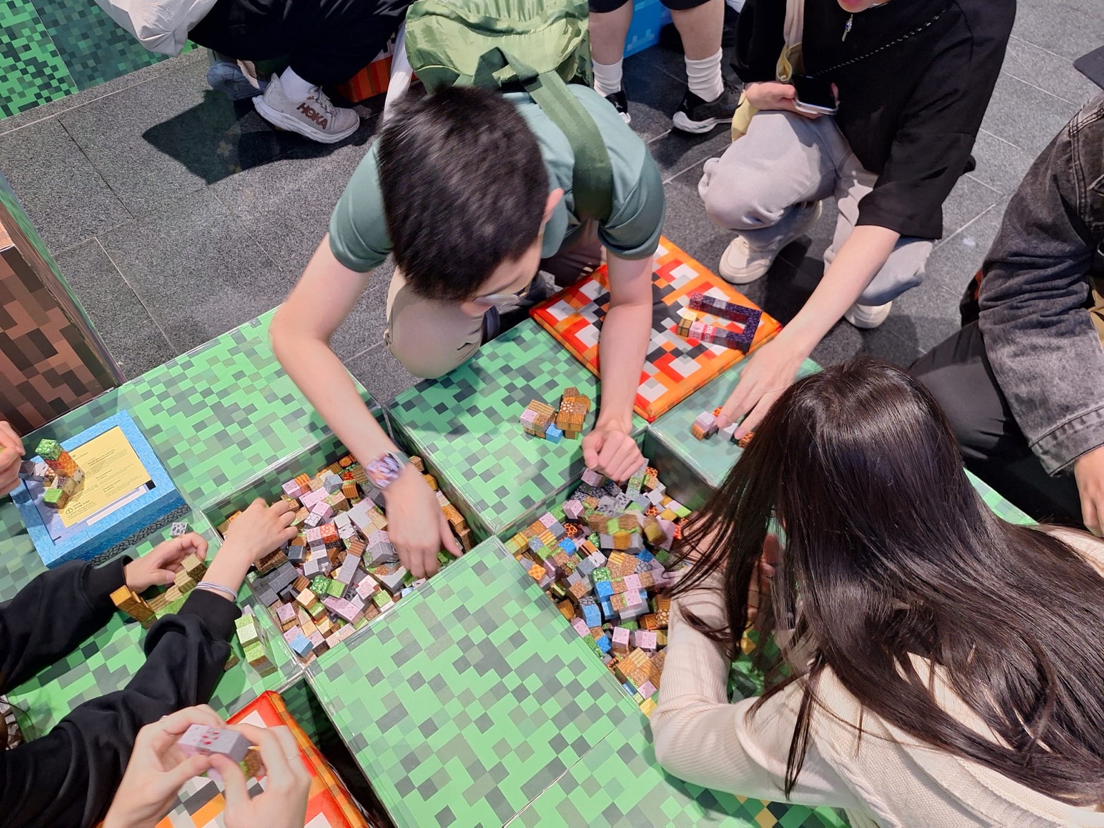 A hands-on table activity, building with green pixel blocks