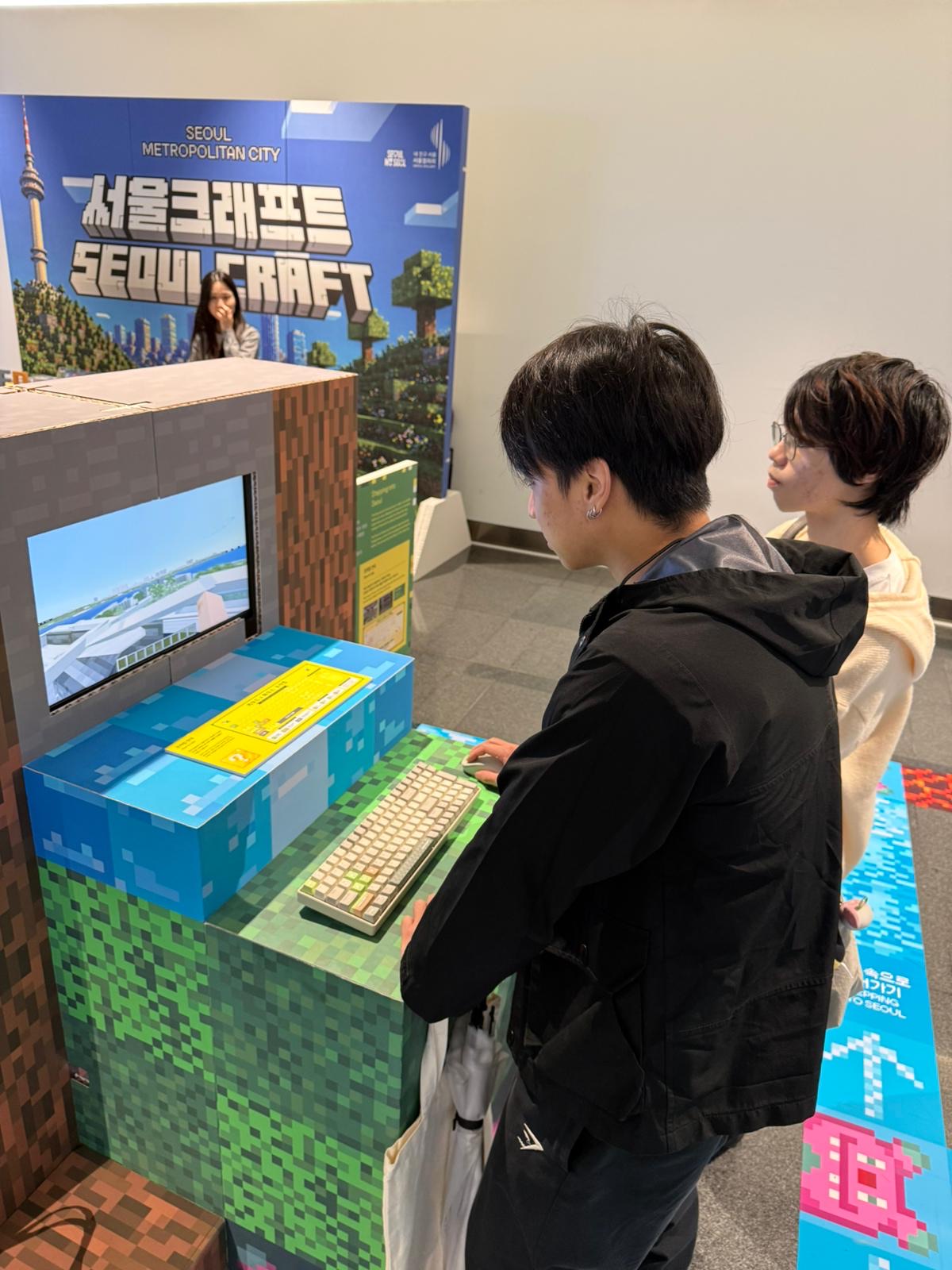 Students playing the Seoul-in-Minecraft station at a keyboard
