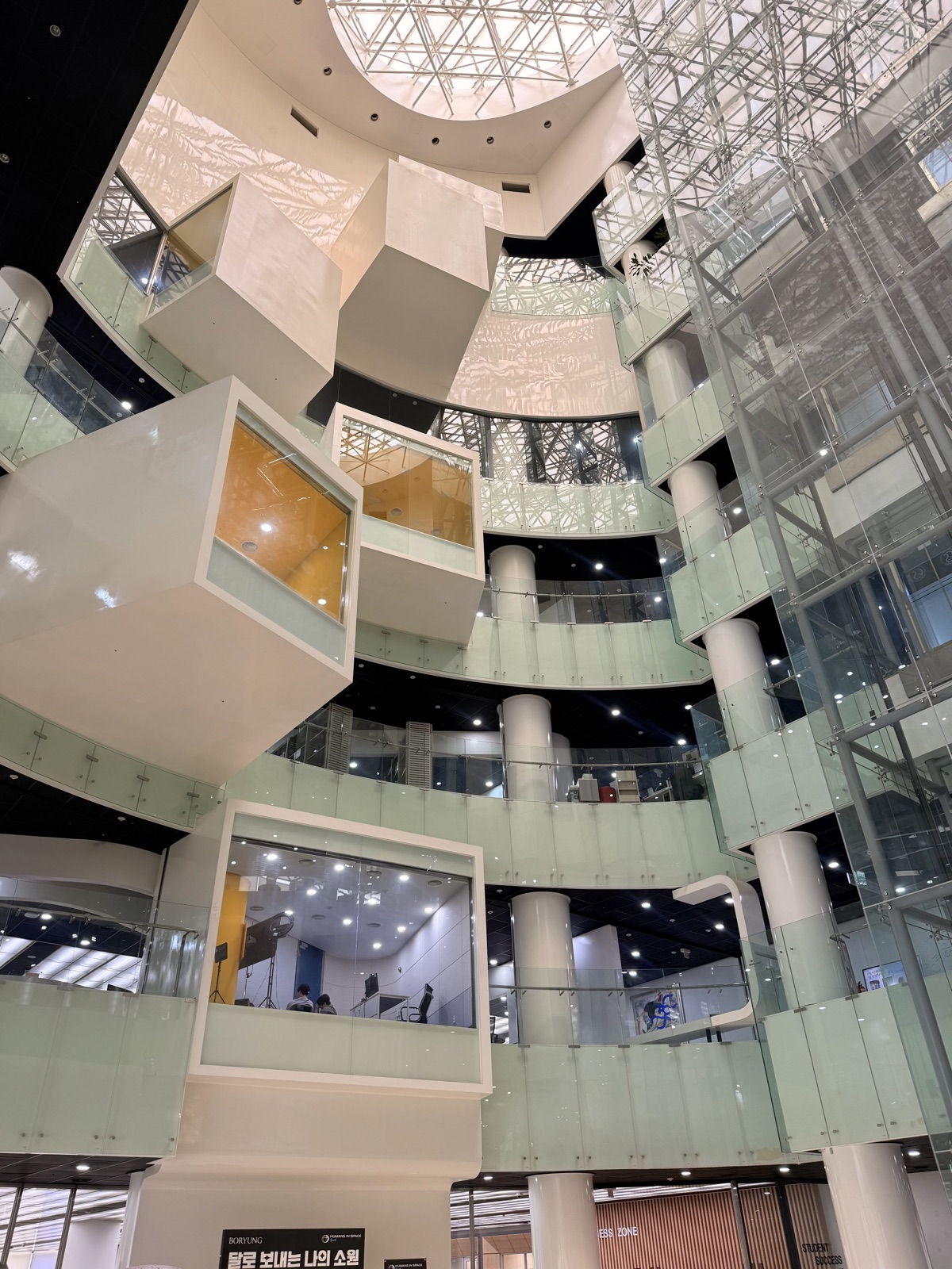 A soaring library atrium with cantilevered white reading pods stacked over many floors