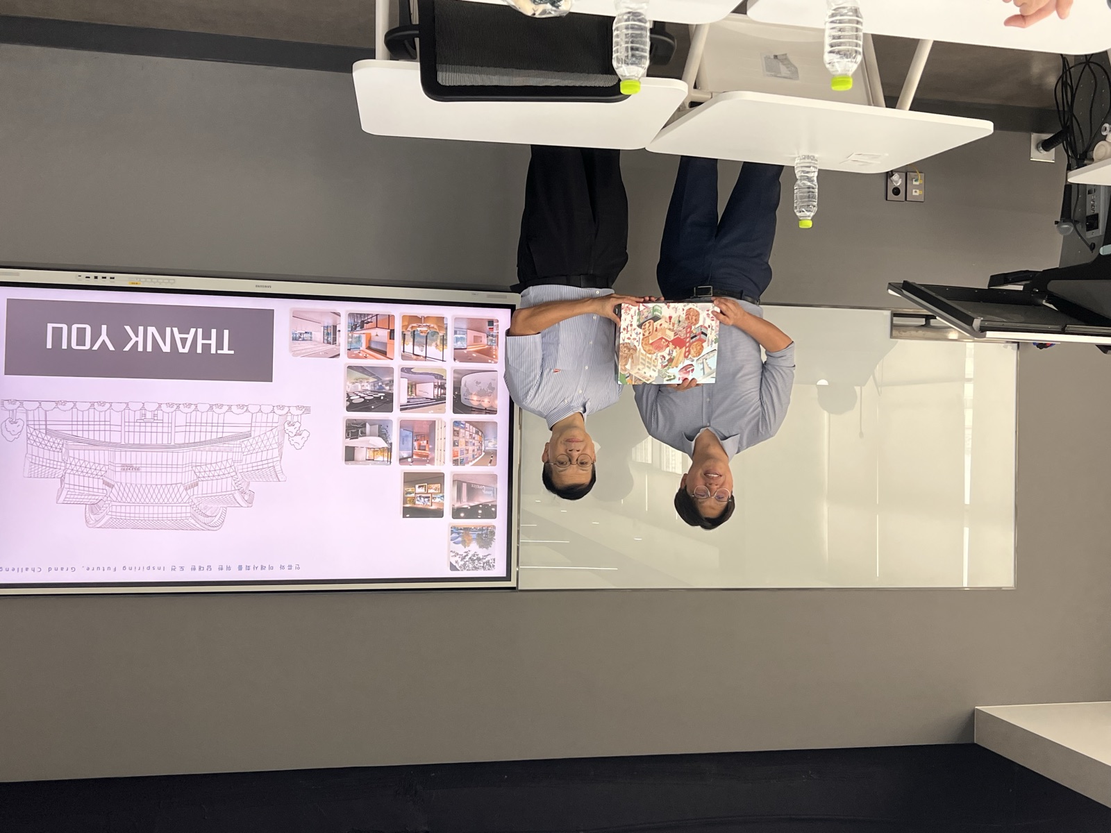 Faculty exchanging a wrapped gift box beneath a THANK YOU slide