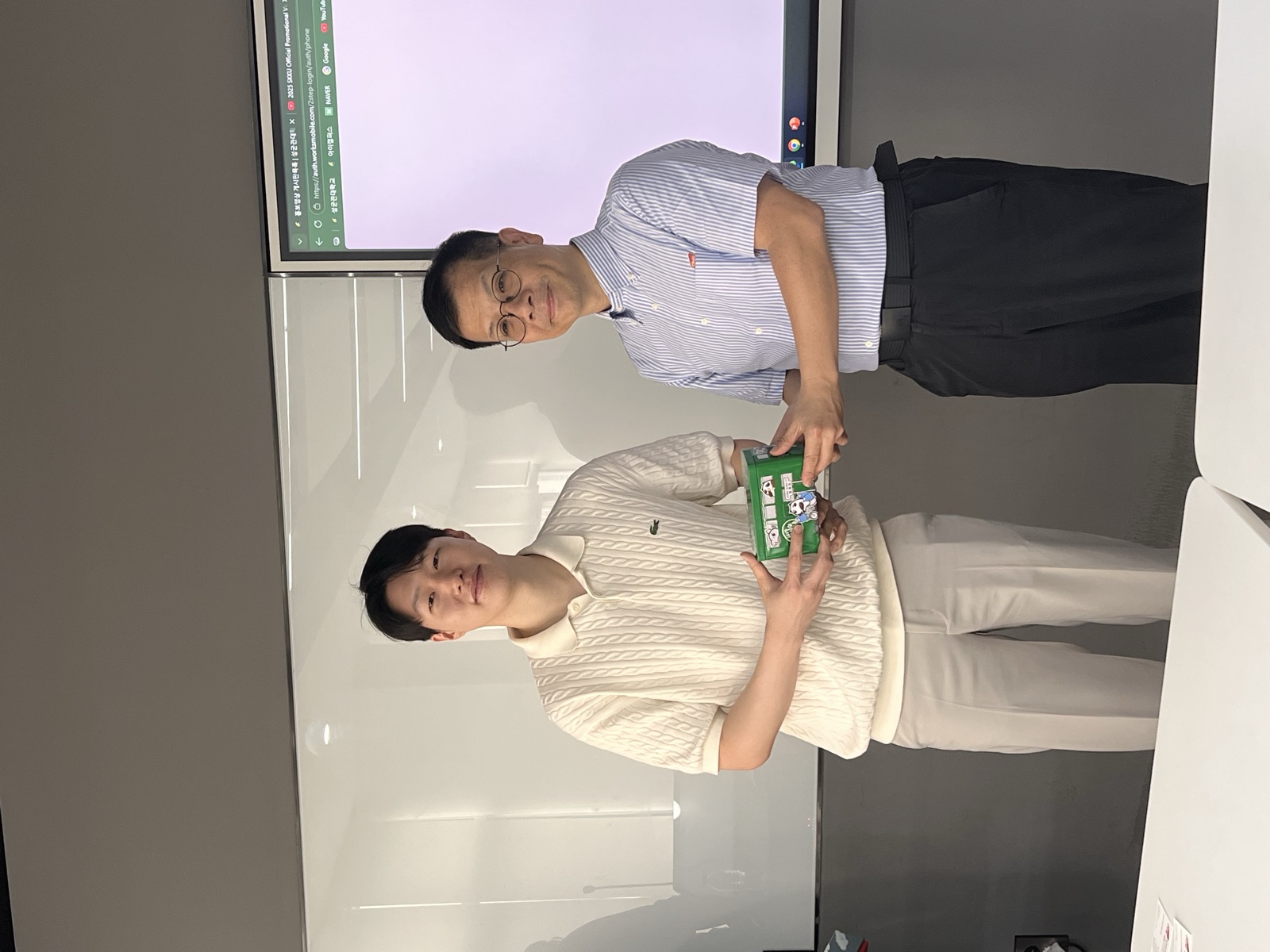 A CityU student receiving a green gift box from an SKKU professor
