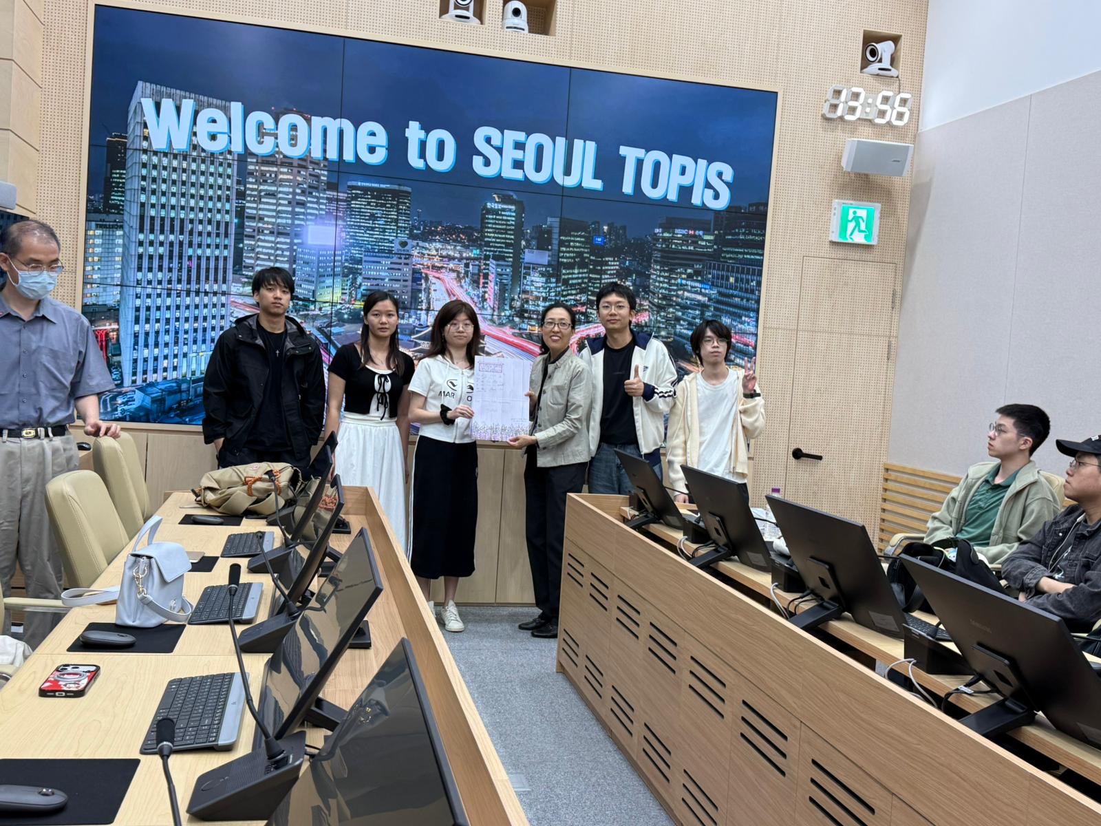 A group photo in the briefing room with the city map lit behind