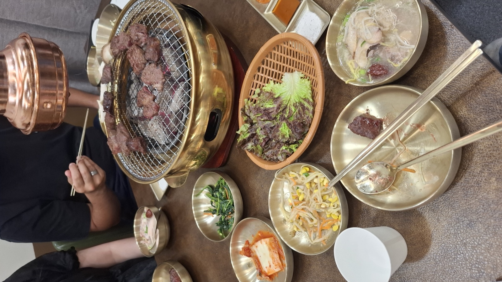 A charcoal grill of Korean BBQ with more banchan than the table could hold