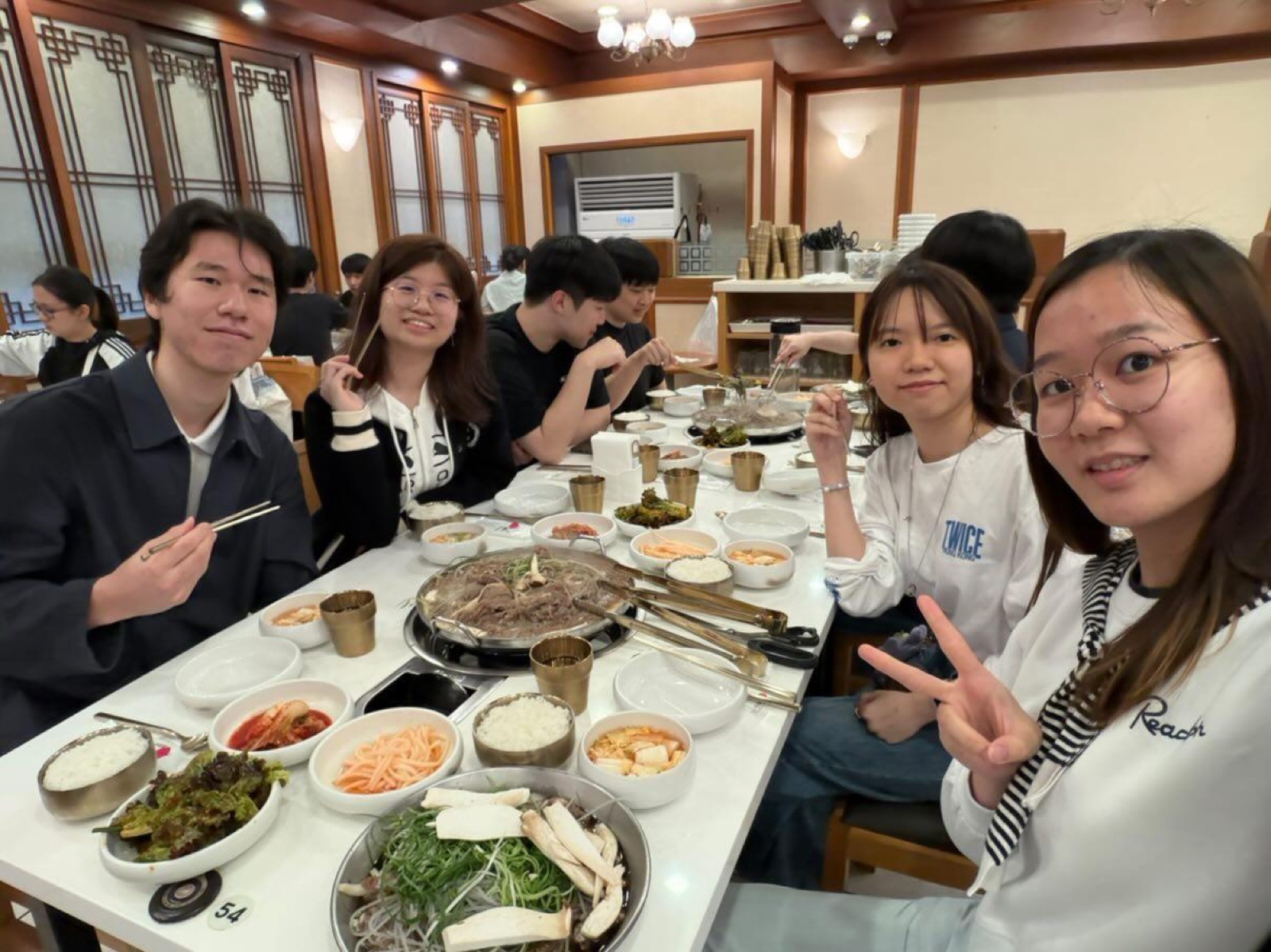 A cheerful group selfie around the dinner table, peace signs up