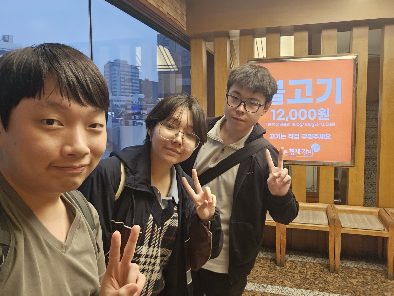 A three-student selfie by the restaurant window