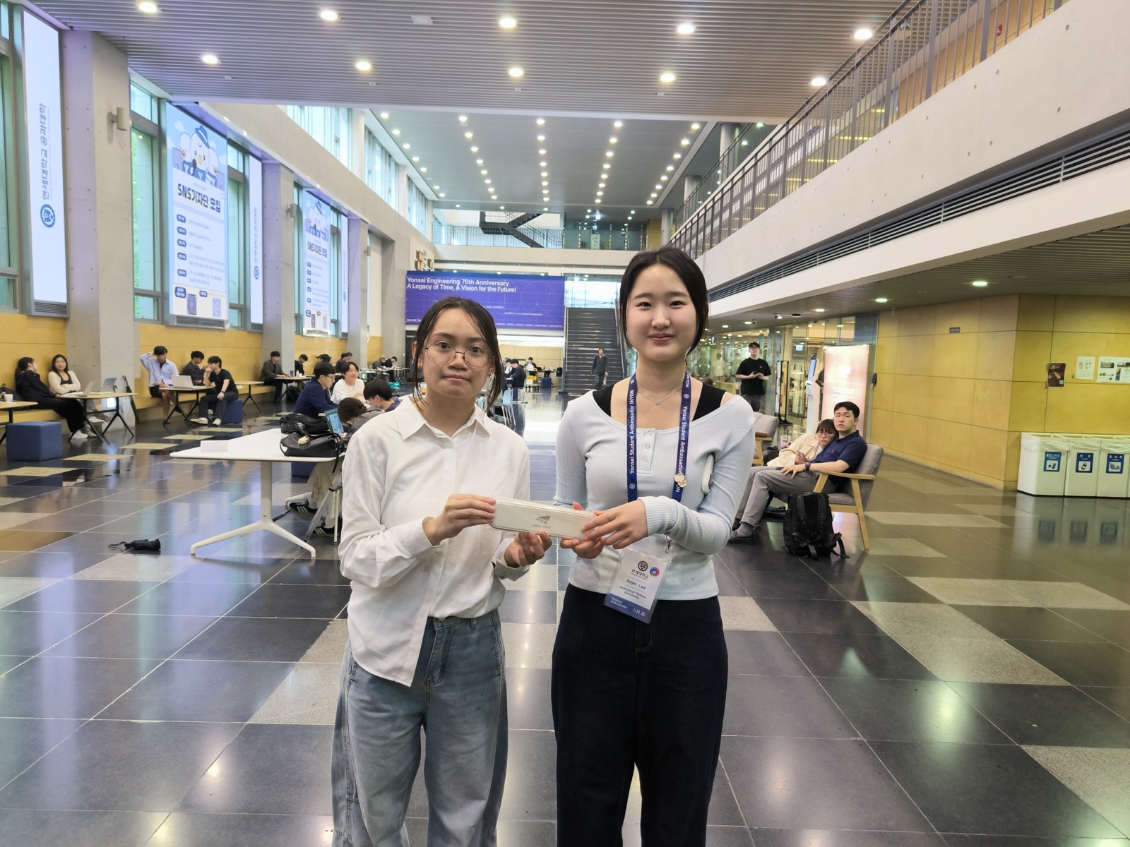 Two students swapping a gift in the glass atrium