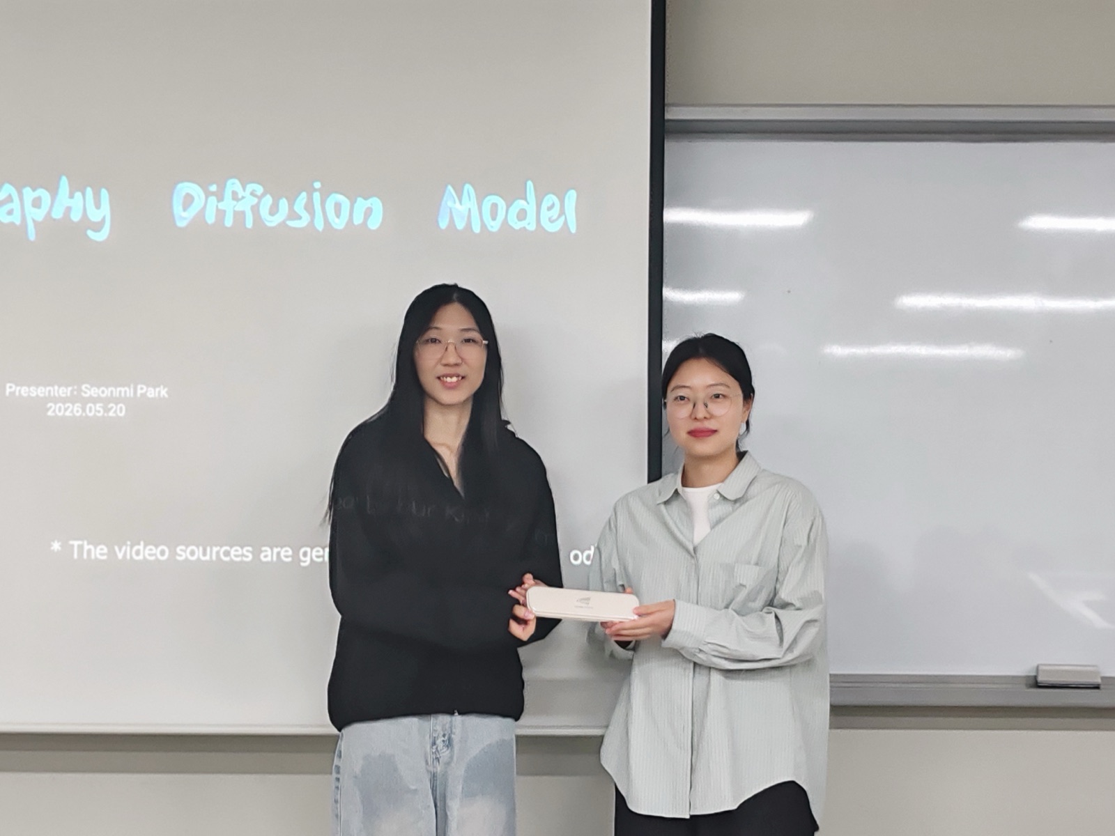 A student gift handover in front of a diffusion-model slide