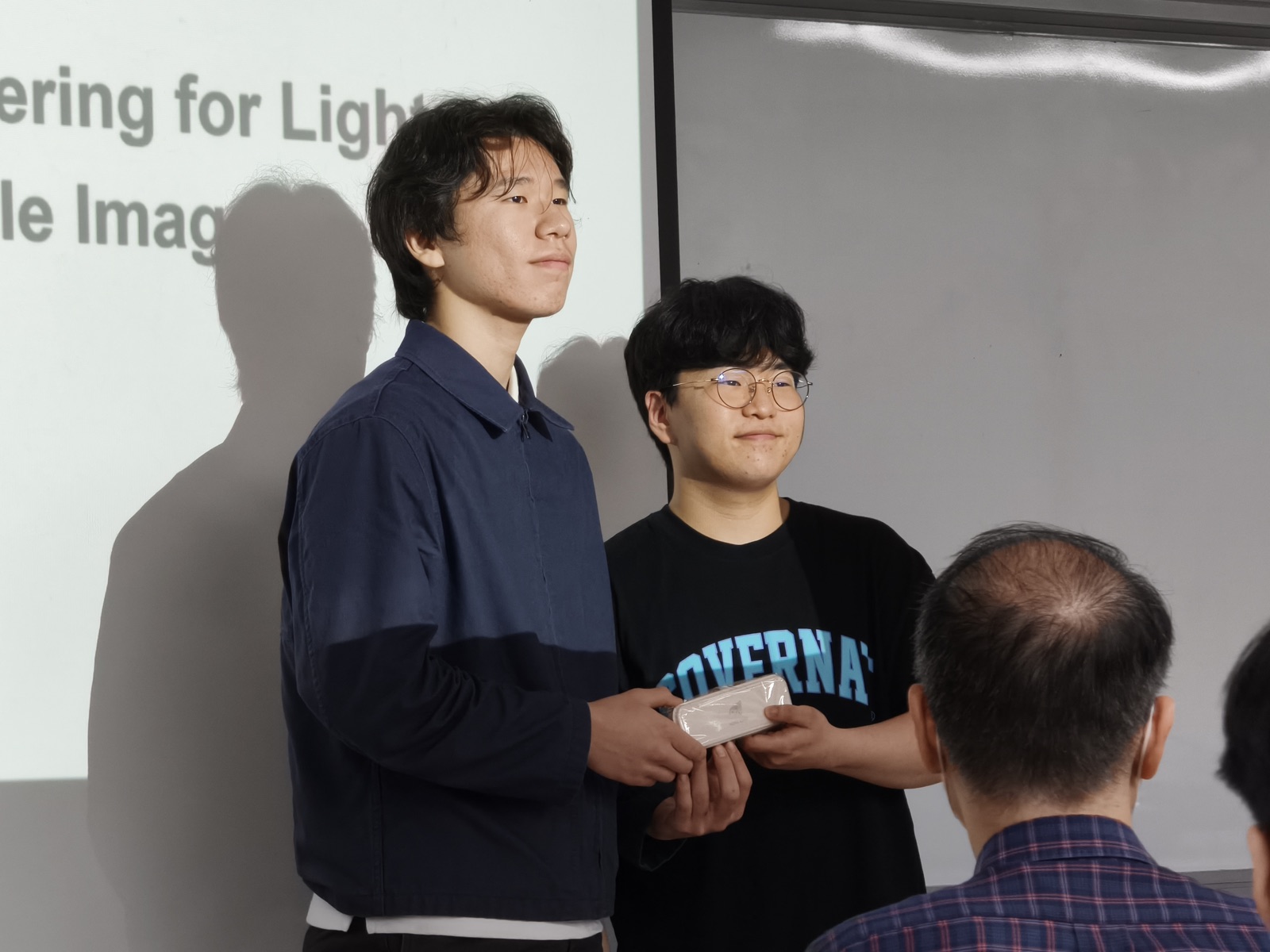 Gifts exchanged beside a rendering-research slide